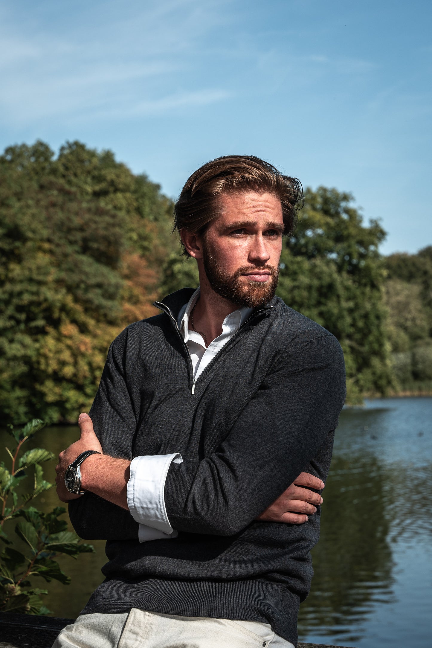 homme avec pull zip cachemire noir avec chemise blanche à coté d'une rivière