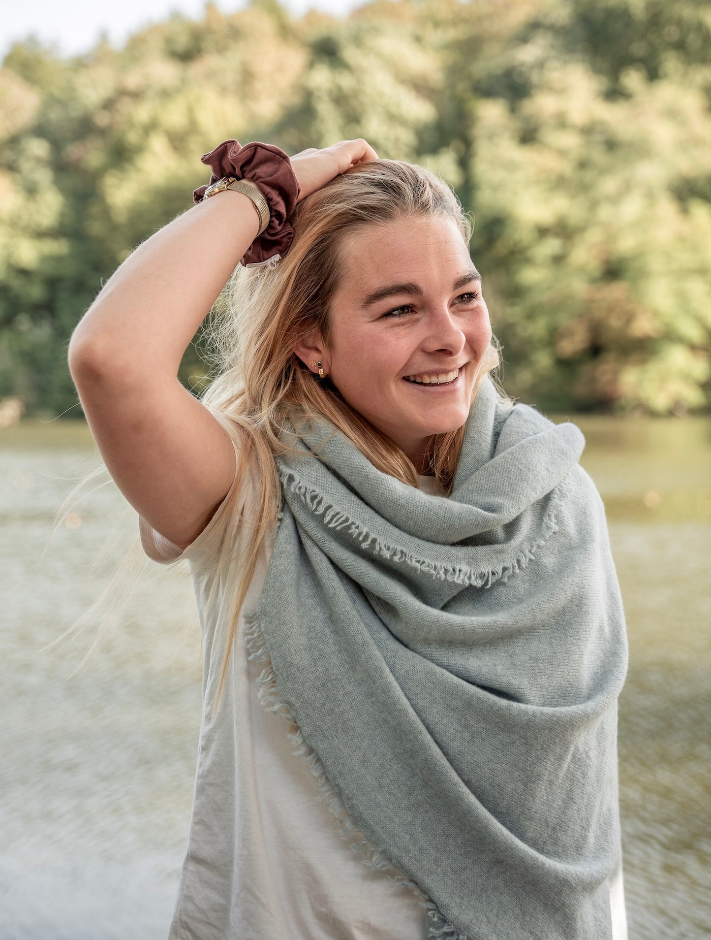 femme blonde avec écharpe grise et tshirt blanc le long d'une rivière